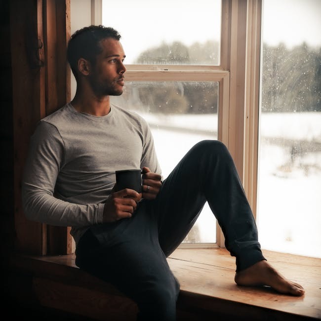 person sitting by window with coffee reflecting in calm natural light